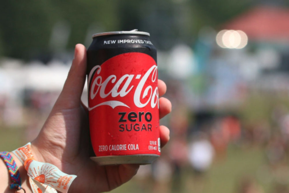Millennial drinking Coke Zero Sugar at a music festival