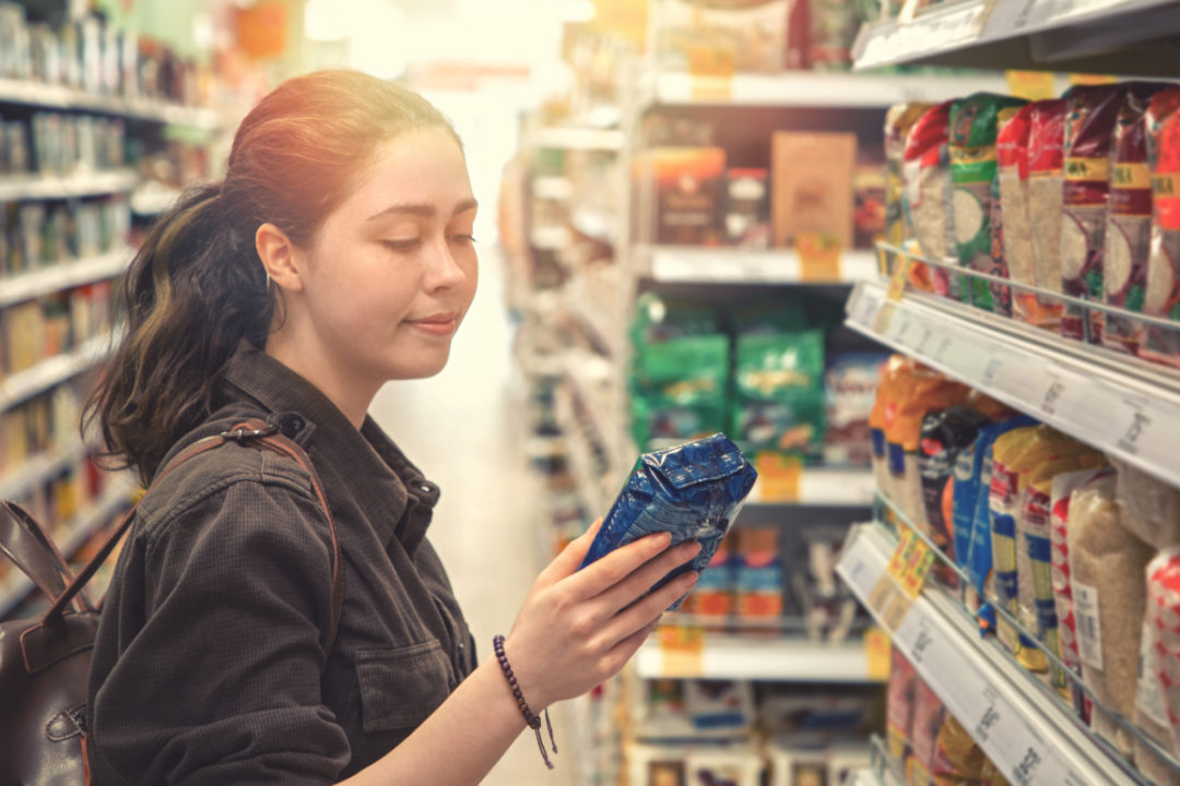 Woman reading food label in supermarket