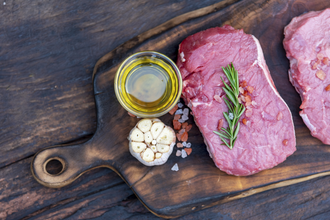 Raw meat beef steak organic fresh ingredient on wooden board table background in kitchen with rosemary, salt, garlic, tomato, black pepper, olive oil.