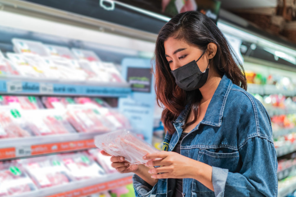 Woman reading food label while wearing face mask