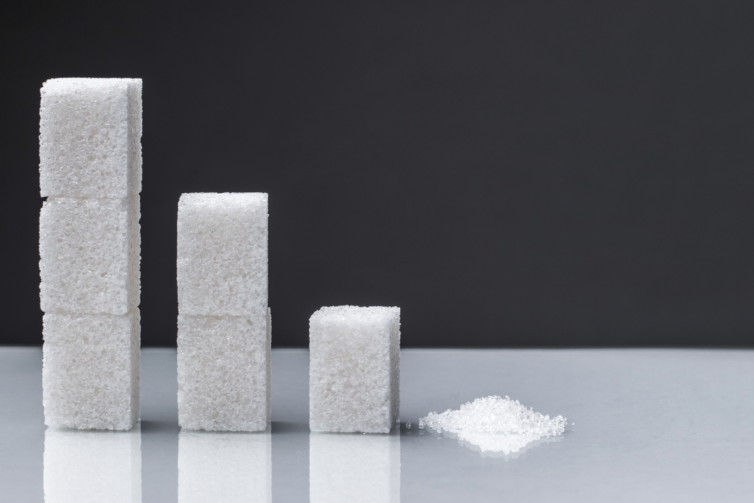 The downward chart is made up of sugar cubes and granulated sugar. Sugar reduction in consumption ?oncept.