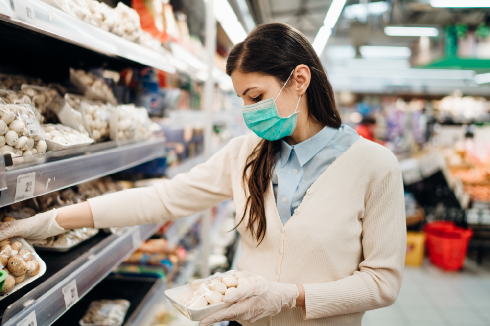 Woman with mask safely shopping for groceries amid the coronavirus pandemic
