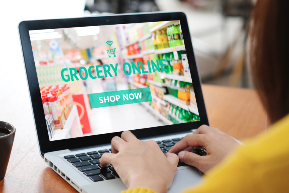 Woman grocery shopping online via laptop