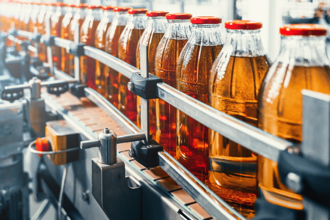 Conveyor belt, juice in glass bottles on beverage plant or factory interior