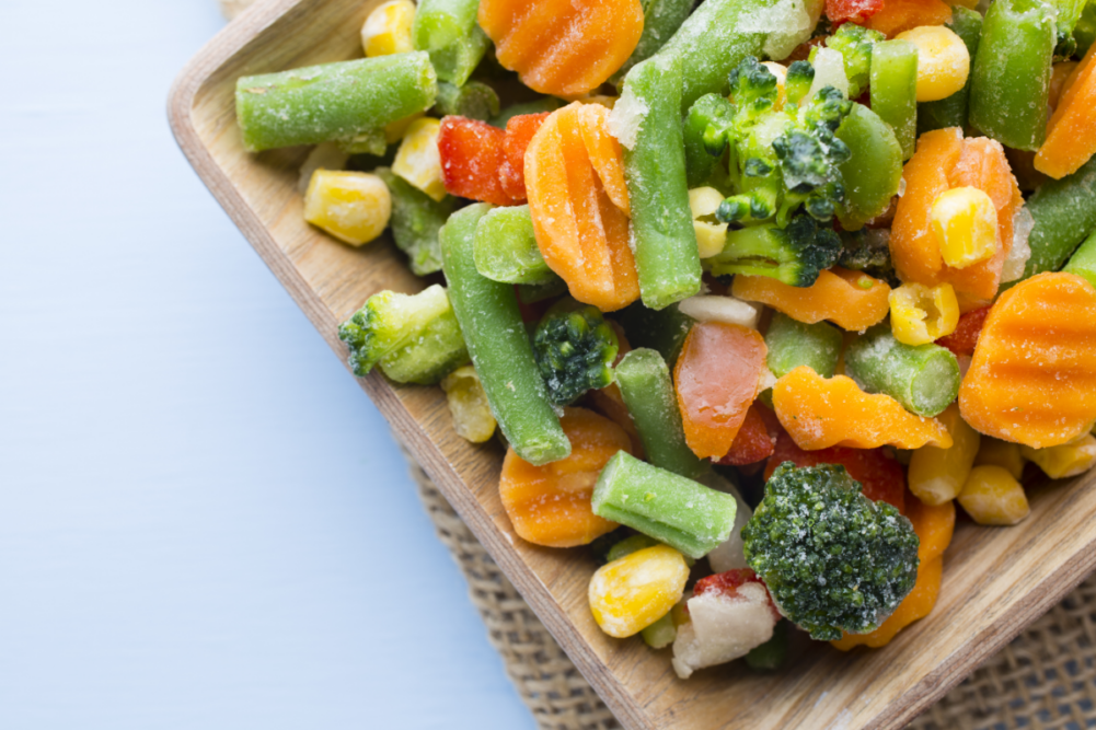 Frozen vegetables on wooden cutting board 