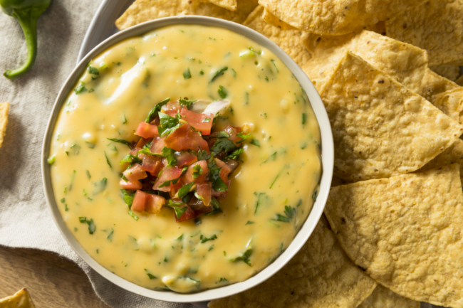 Spicy homemade cheesey queso dip in a bowl with tortilla chips 