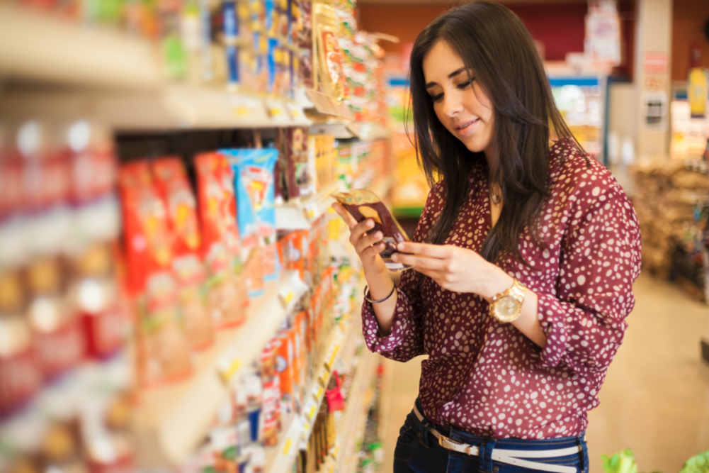 Woman in a grocery store looking at the label on a food package