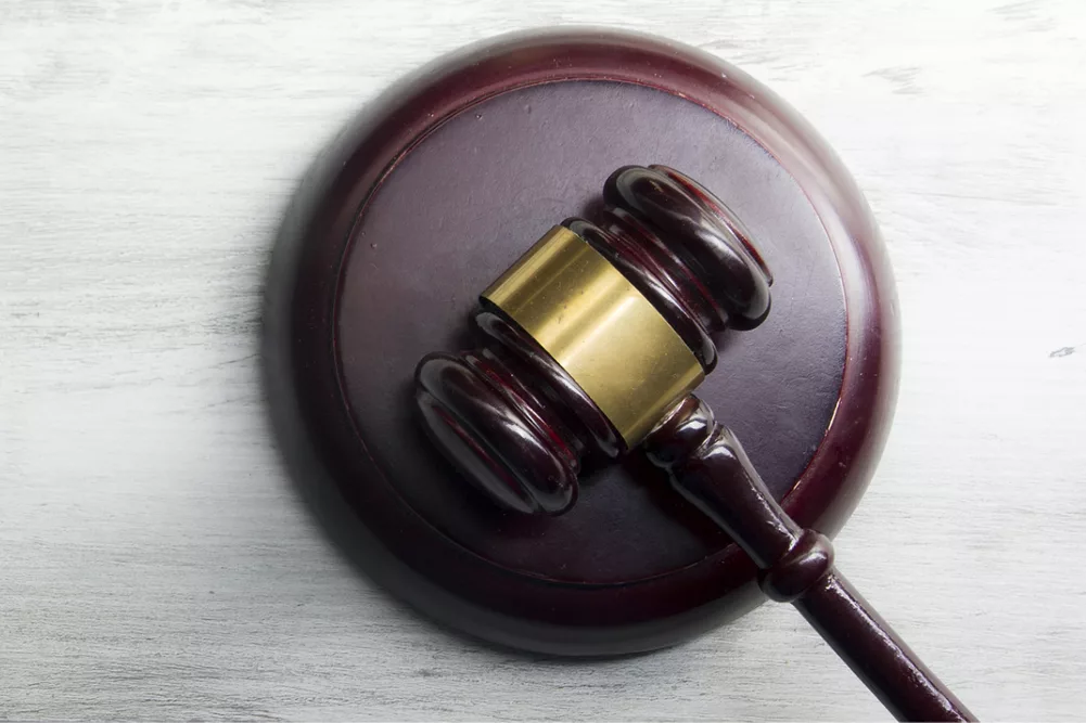 Open law book with a wooden judges gavel on table in a courtroom