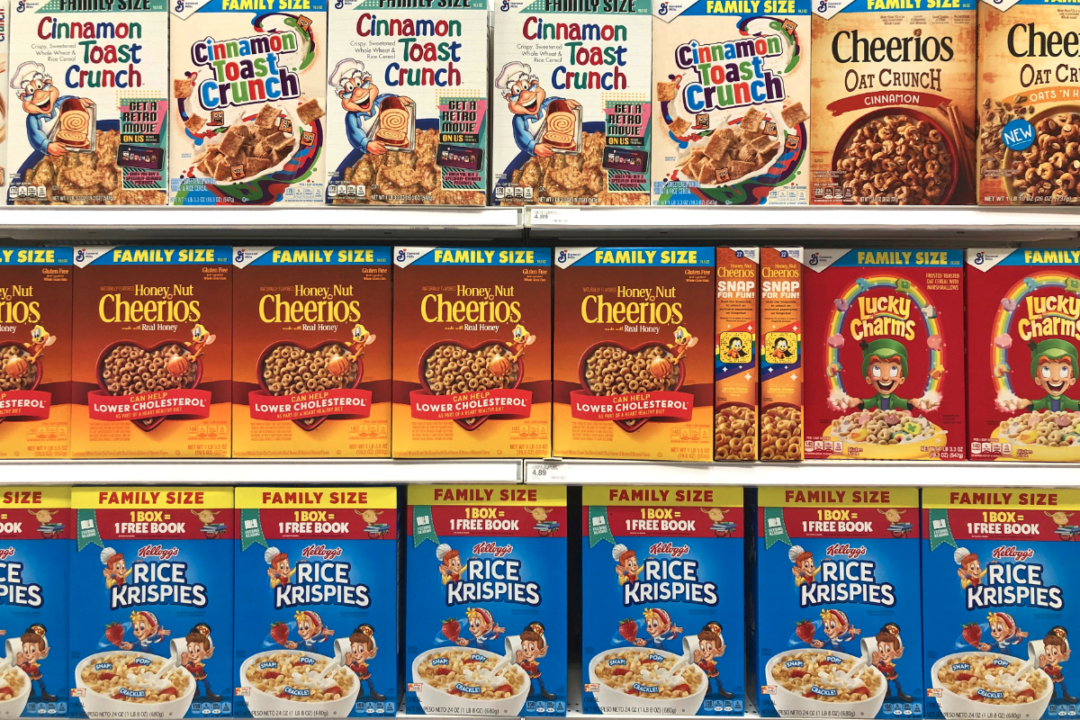 Grocery store shelf with boxes of General Mills and Kellogg's brands cereals