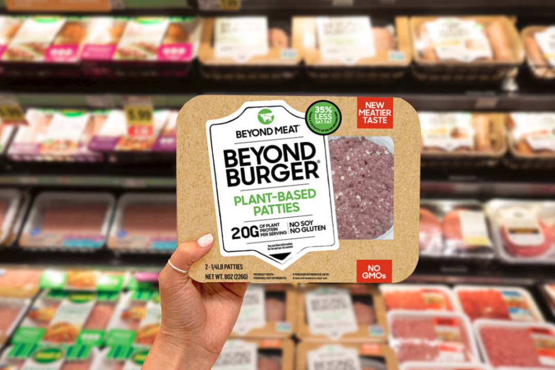Hand holding Beyond Burger package in grocery store meat aisle 