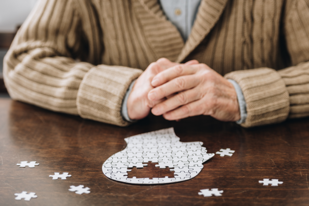 cropped view of senior man playing with puzzles on table