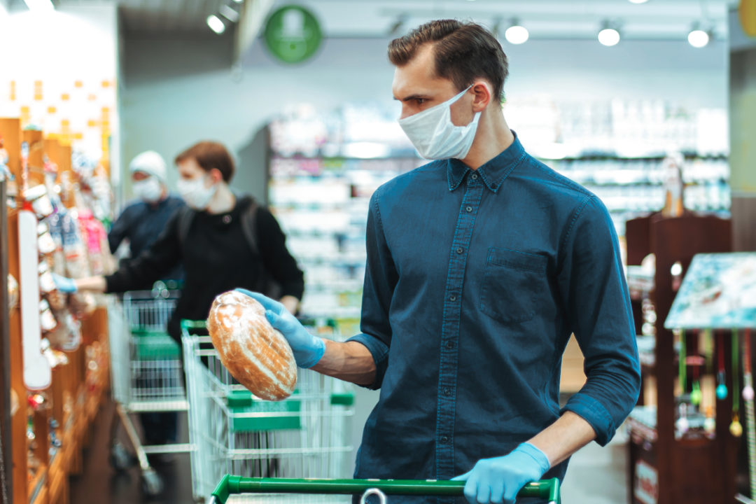 Man wearing face mask shopping for bread in a supermarket