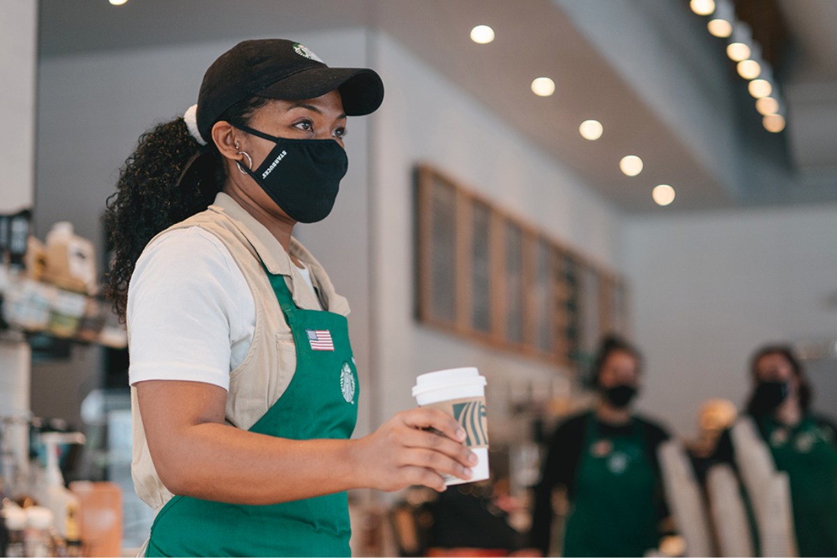 Starbucks barista wearing a mask giving a customer coffee