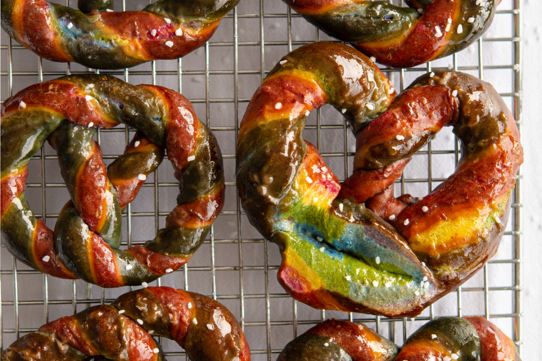 Jumbo rainbow colored pretzels on cooling rack