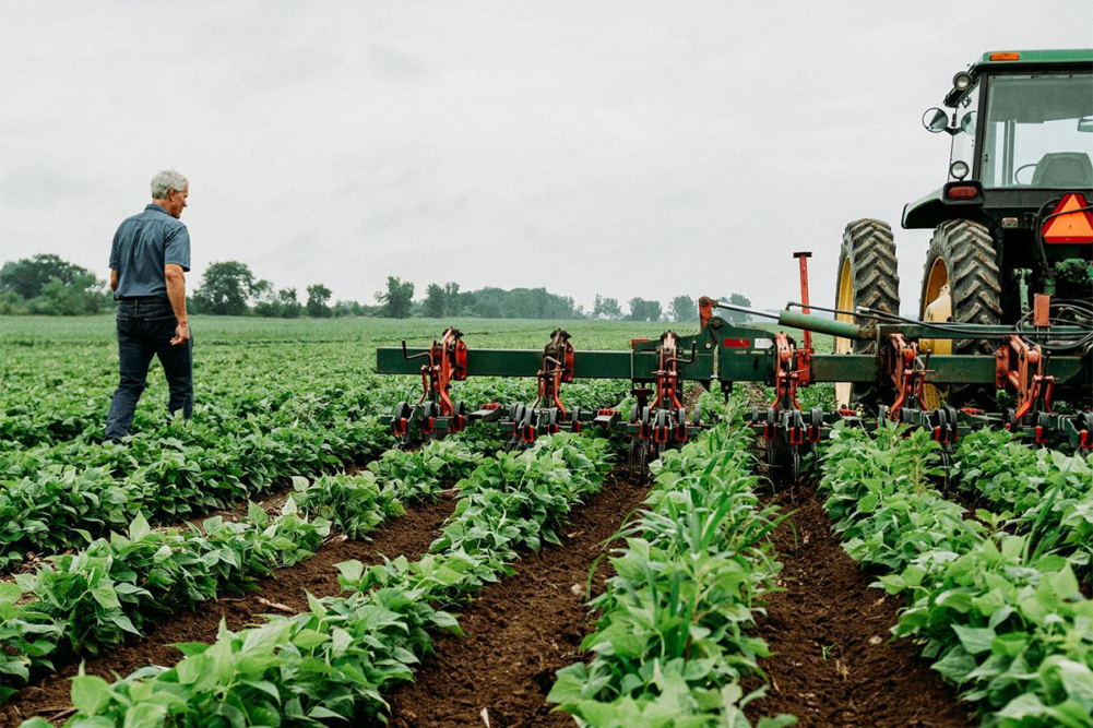 Man walking in a field next to a tractor