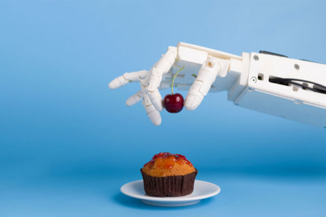 Robot hand putting a cherry on a cupcake