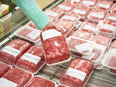 Woman choosing packaged meat from grocery store