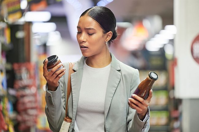 Woman comparing two products in a supermarket