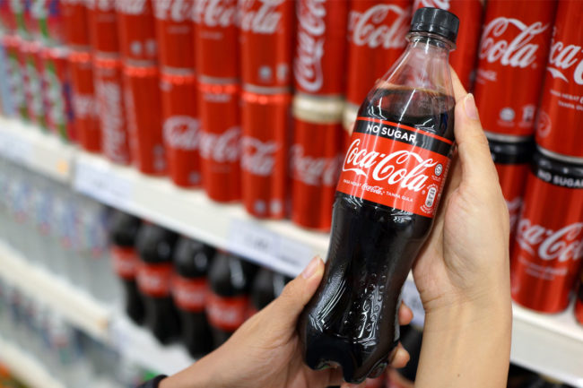 A consumer holding a Coca-Cola soda