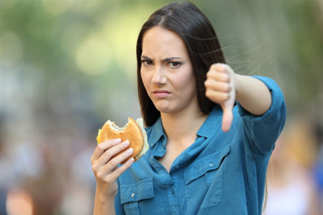 Woman with burger giving thumbs down