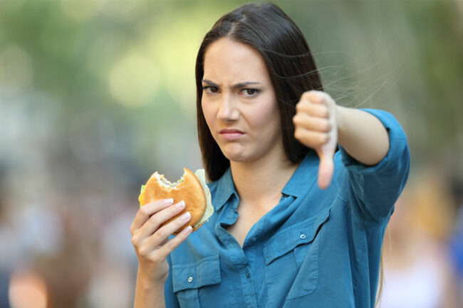 Woman with burger giving thumbs down