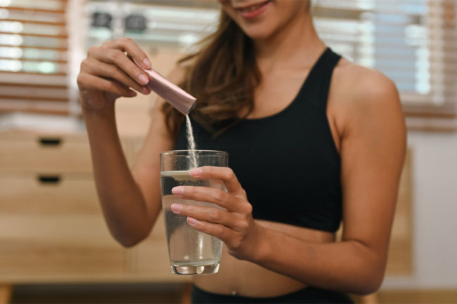 Woman pouring collagen powder into water