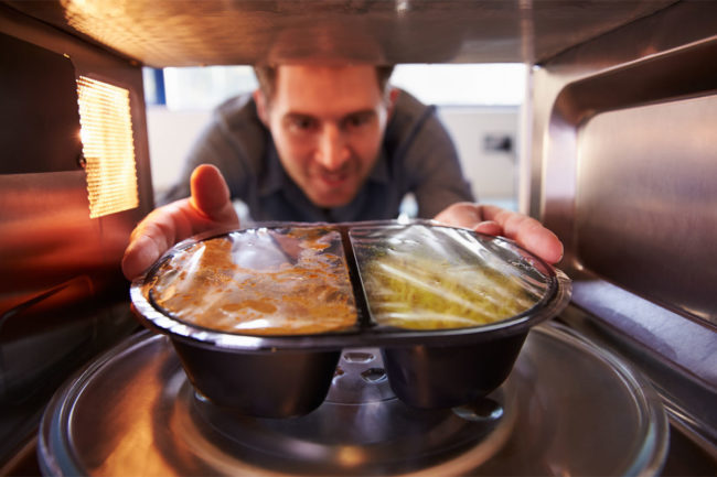 Man putting meal into the microwave