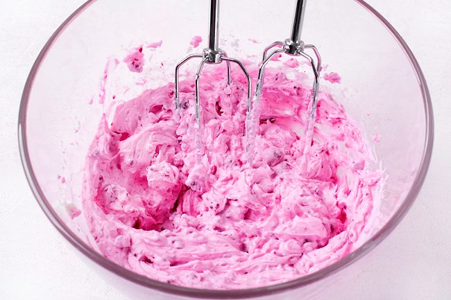 Pink whipped cream in mixing bowl
