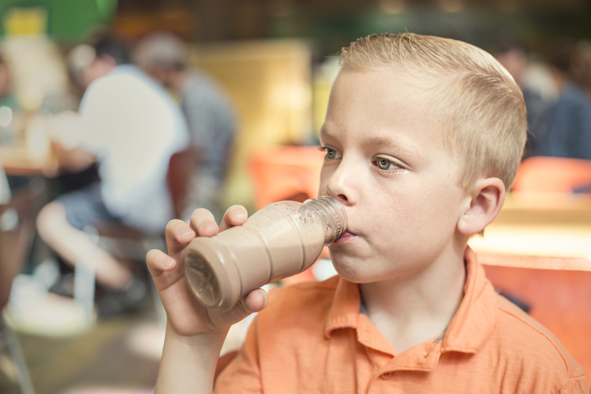Boy drinking chocolate milk with school lunch