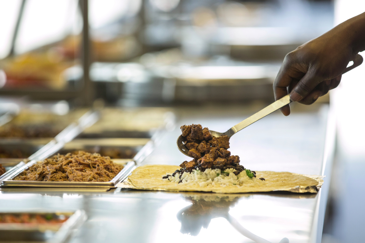 Chipotle employee serving steak